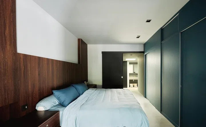 The master bedroom of this 1,189 sq ft single-storey corner terrace house in Siglap was lined with dark walnut wood bed headboard and matching teal wardrobes
