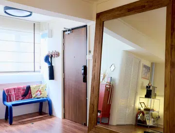 Entrance foyer chair and oversized mirror by the main door in a 5-room HDB flat in Yishun, designed by Homely Matters Pte Ltd.