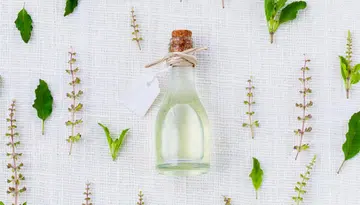 Image of a clear bottle with herbs around. DIY mosquito repellent