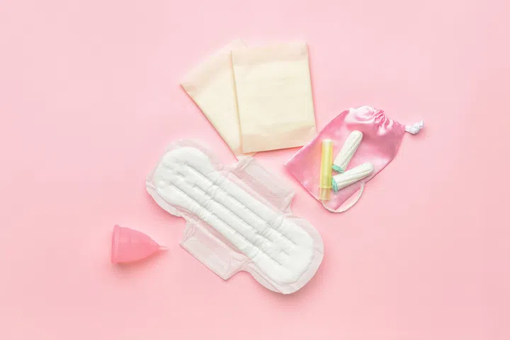 Menstrual cup, pads and tampons on pink background