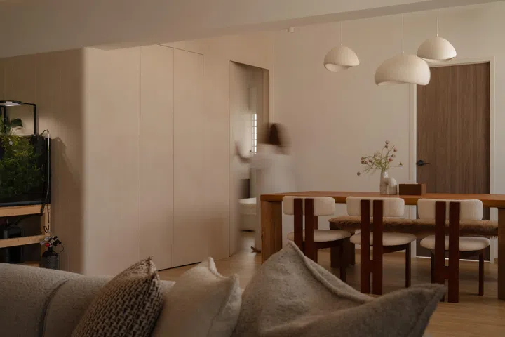 The dining area is framed by pale timber joinery that conceals doors and storage, keeping the space visually calm and uncluttered.