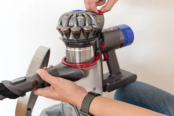 A pair of hands opening up the Dyson V8 Fluffy head and removing the motor and HEPA filter.