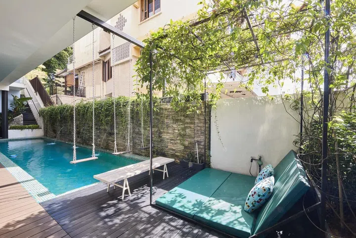 A swimming pool with swings and deck chairs in the home office wing of interior designer Cheryl Gay of Coterie Design's 3,600 sq ft semi-detached home in Yio Chu Kang.