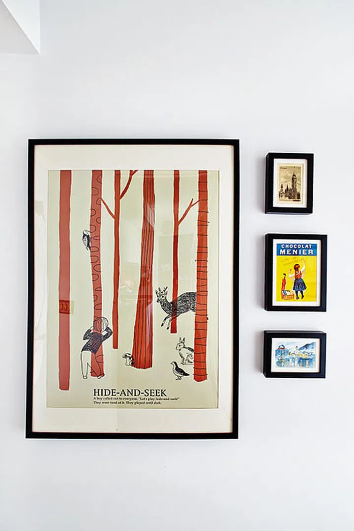 The combined height of three smaller poster art frames balances the large poster frame. Interior design by JQ Ong at The Association.