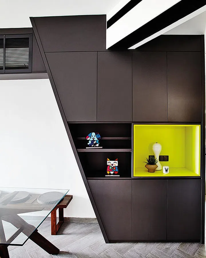The black and lime laminate feature wall by the dining table contains storage for items such as crockery that the couple need for entertaining. The air-conditioner is also concealed within.