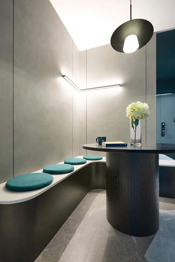 A compact dining nook with a custom-sized table, green-cushioned bench seating, and a muted backdrop.