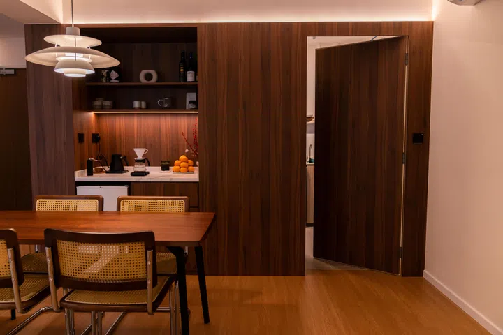 The concealed kitchen door is finished in matching wood veneer, allowing it to blend seamlessly with the dry pantry and dining cabinetry.