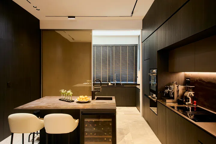 A long island anchors the kitchen, combining preparation, casual dining, and storage within a compact, highly efficient layout.