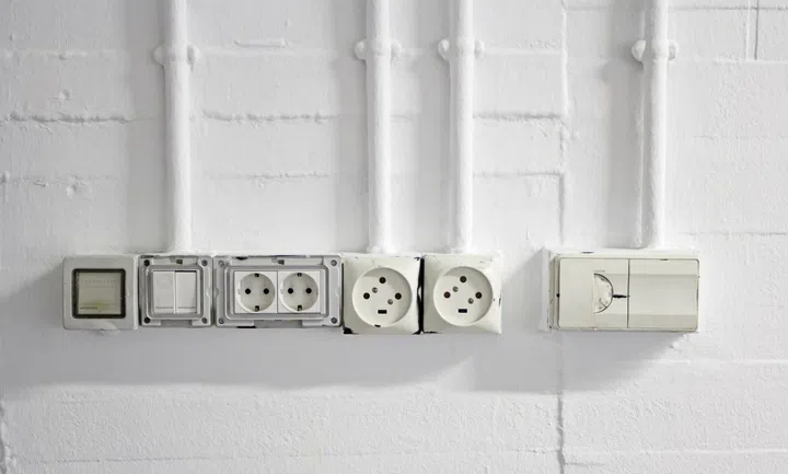 White brick wall with plugs and switches, electrical installation.