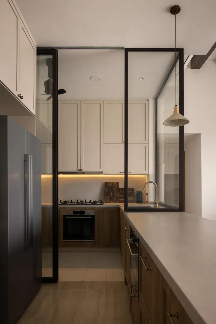 You enter the wet kitchen via the dry kitchen. The two kitchens are divided by a stylish glass and black framed sliding door. The petal-shaped pendant light across the dry kitchen island is from Taobao. 