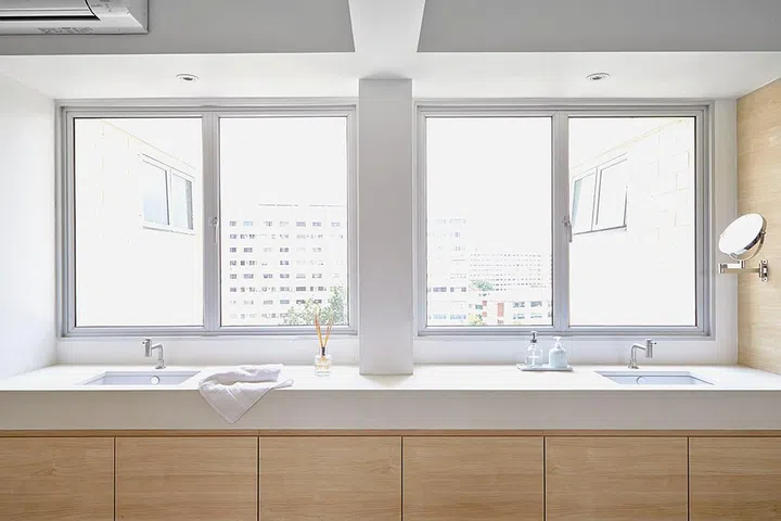 The double-sink vanity top near the bed is supported by deep cabinetry. By storing all of their toiletries in it, this jumbo HDB home's uncluttered appearance is easily maintained. Image by Desmond Ong.