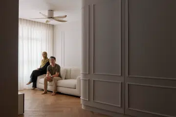 A couple in their early 30s, Trisha and Leon, poses for a photo in their living room of their 4-room HDB BTO (1,004 sq ft) in Bishan, designed by RENOSTUD.IO.