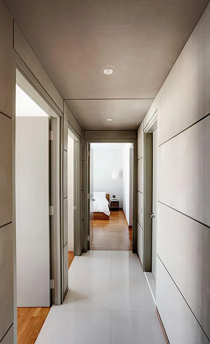 A corridor lined in concrete panels lead to the bedrooms.