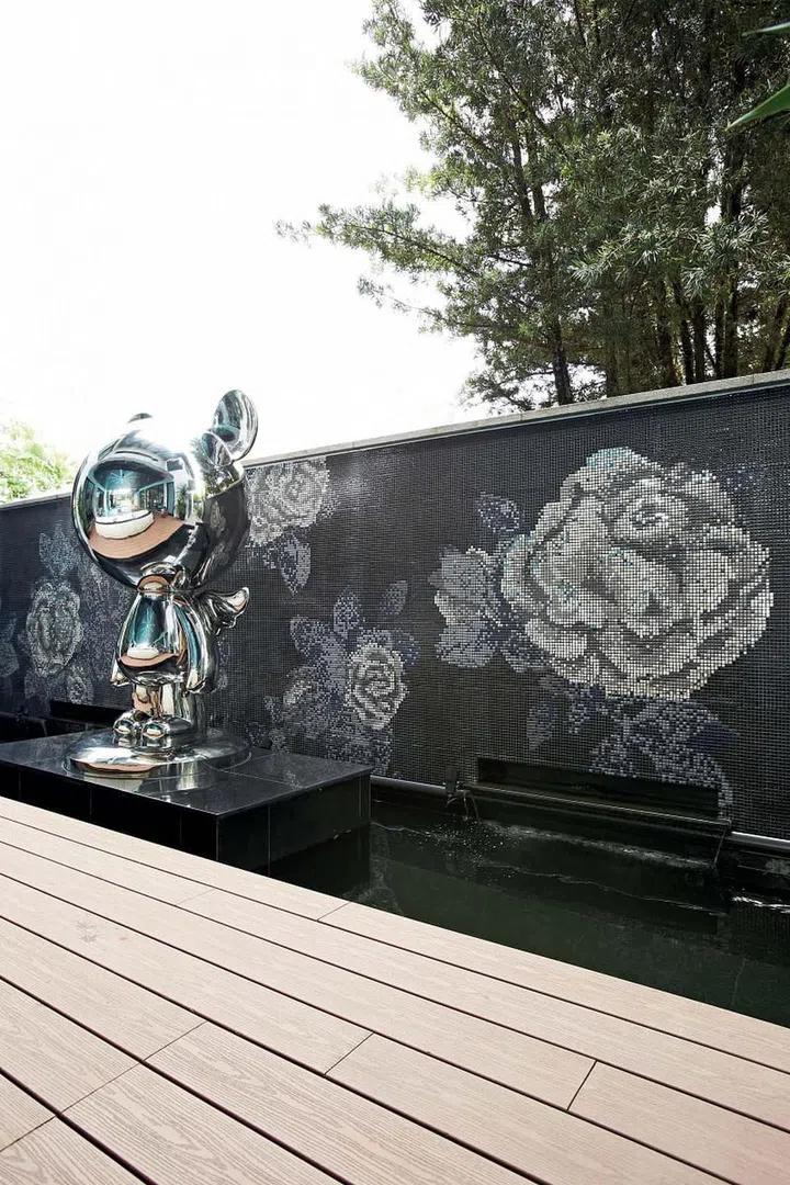 Beside the swimming pool, the specially ordered Angel Bear sculpture complements the glitz of the rose-motif mosaic wall behind it. 
