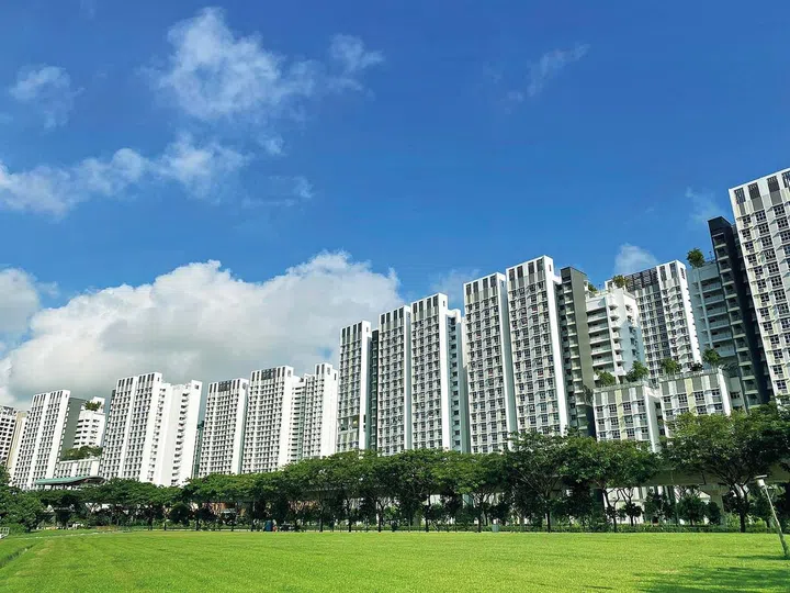 Distant view of residential apartment (HDB) with empty field under cloudy sky