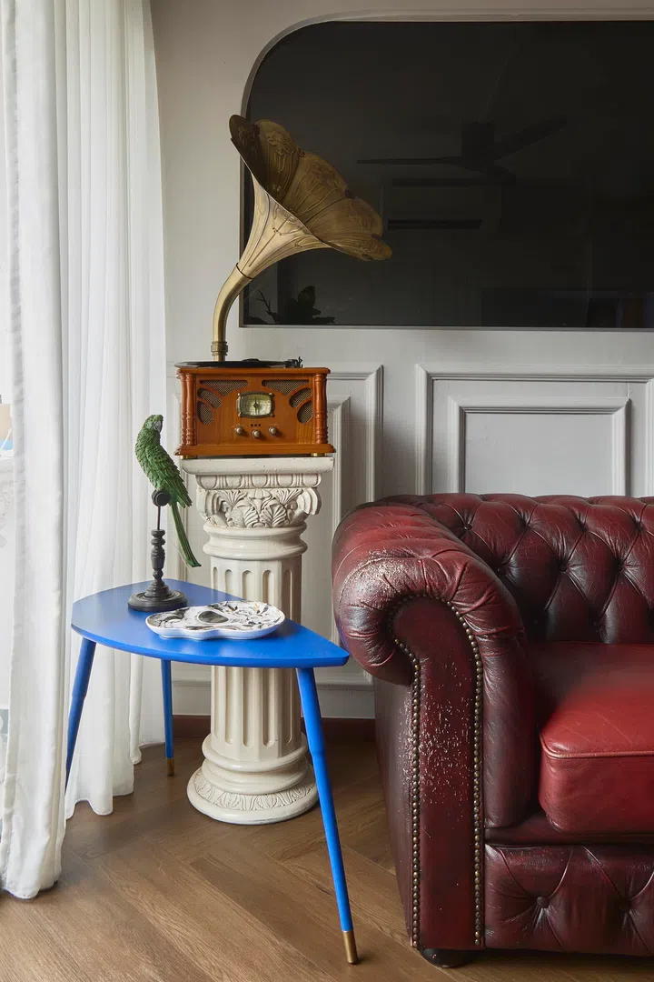 A gramophone displayed on a pedestal sourced from Carousell sits beside a Chesterfield sofa chosen for how it ages over time.