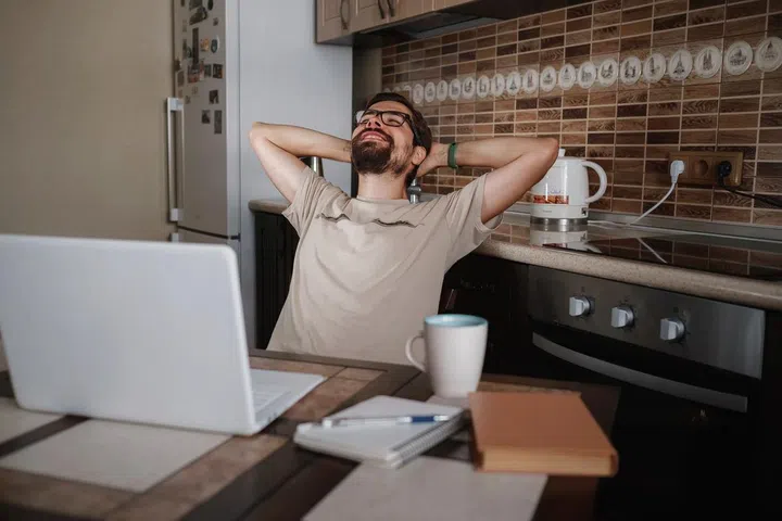 Young man in the kitchen at home with a laptop and a cup of coffee. Photo 123RF
