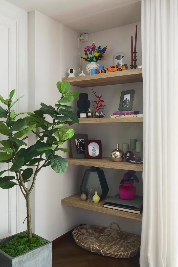 Open shelves display a rotating mix of personal objects, photographs, and collected items, reinforcing the home’s constantly evolving nature.
