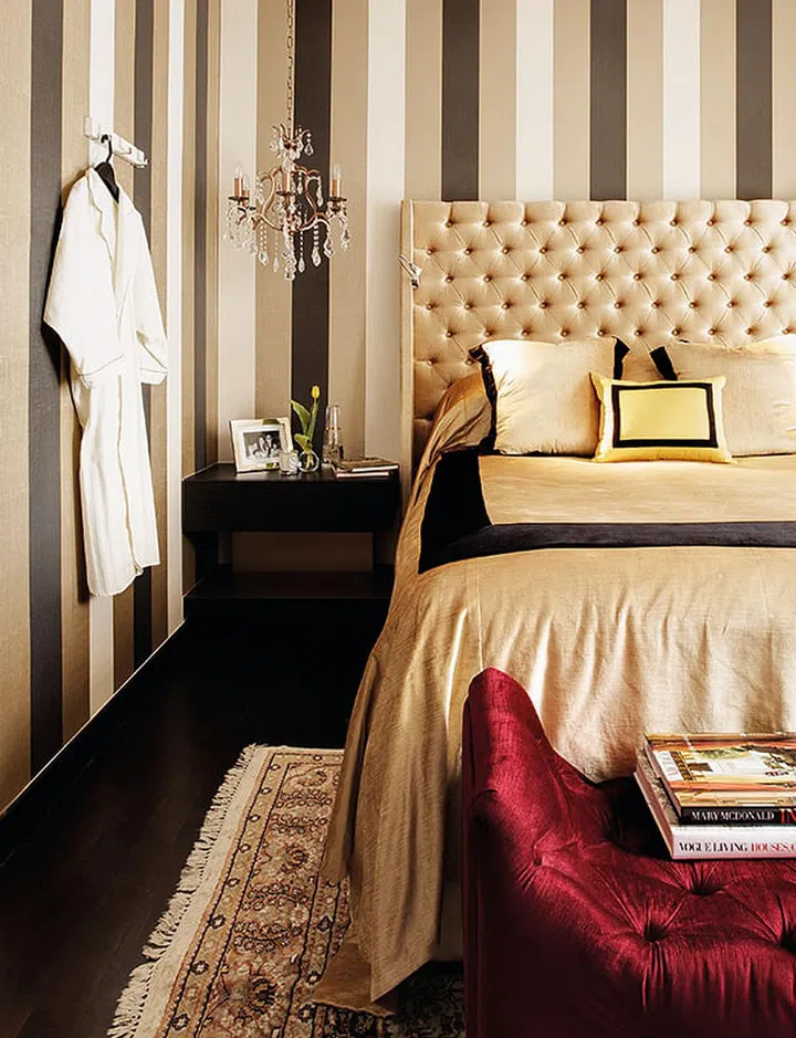 Hints of gold in the textured wallpaper give the room an intimate feel. Touches of claret and rose were added for visual contrast, and crystal chandeliers brought glamour into the space.