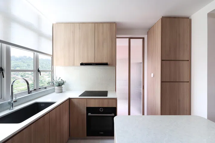 Framed by warm wood, the glass panels slide open to blur the boundaries between kitchen and living space.