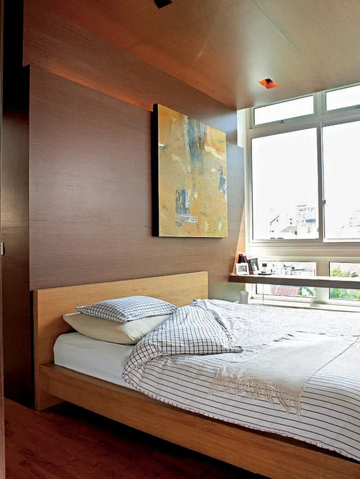 A wenge veneer feature wall continues up the ceiling to enfold the small master bedroom in earthy, muted warmth.