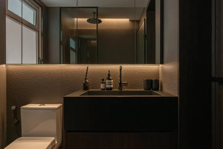 The master bathroom pairs textured walls with warm timber and concealed lighting for a calm, understated retreat.