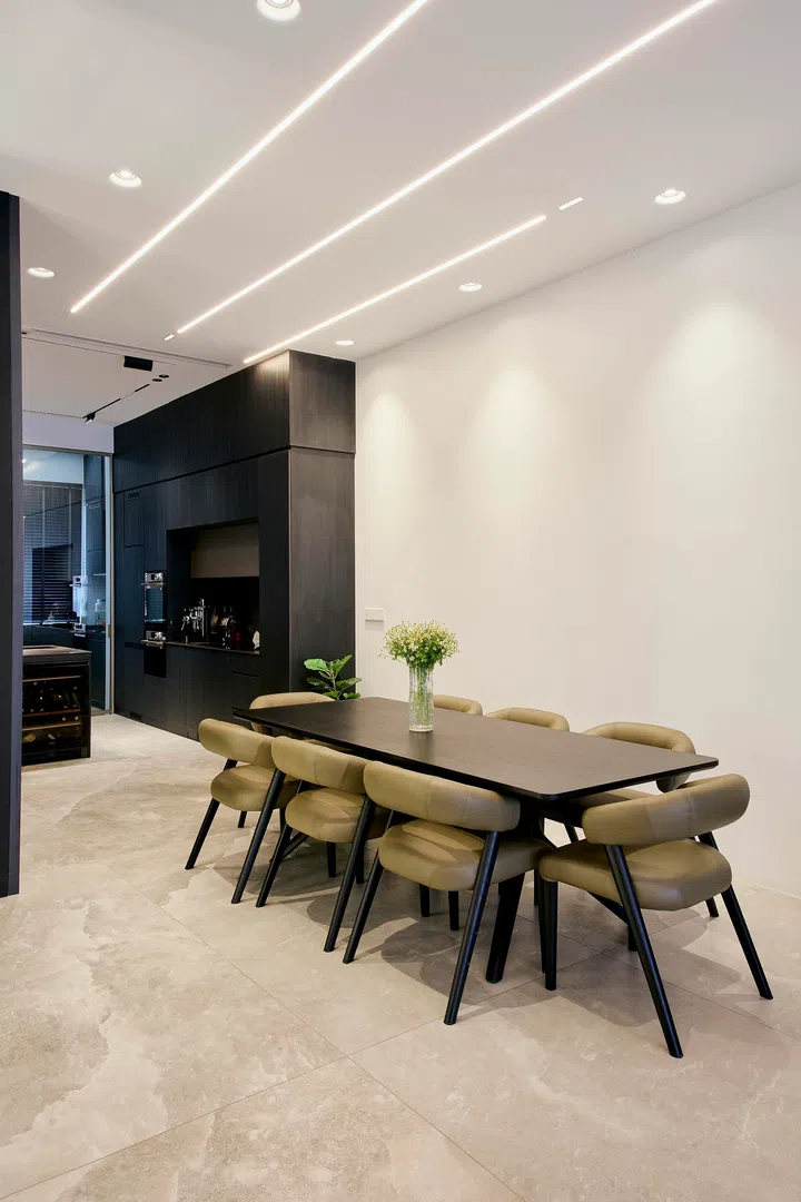 The dining area sits within the open-plan layout, defined by alignment and lighting rather than partitions, establishing a seamless connection between the living room and kitchen.