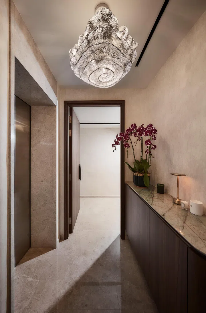 A continuous sequence unites the living, dining and bar areas, where travertine flooring, walnut cabinetry and subtly layered lighting form a warm, cohesive backdrop for everyday living.