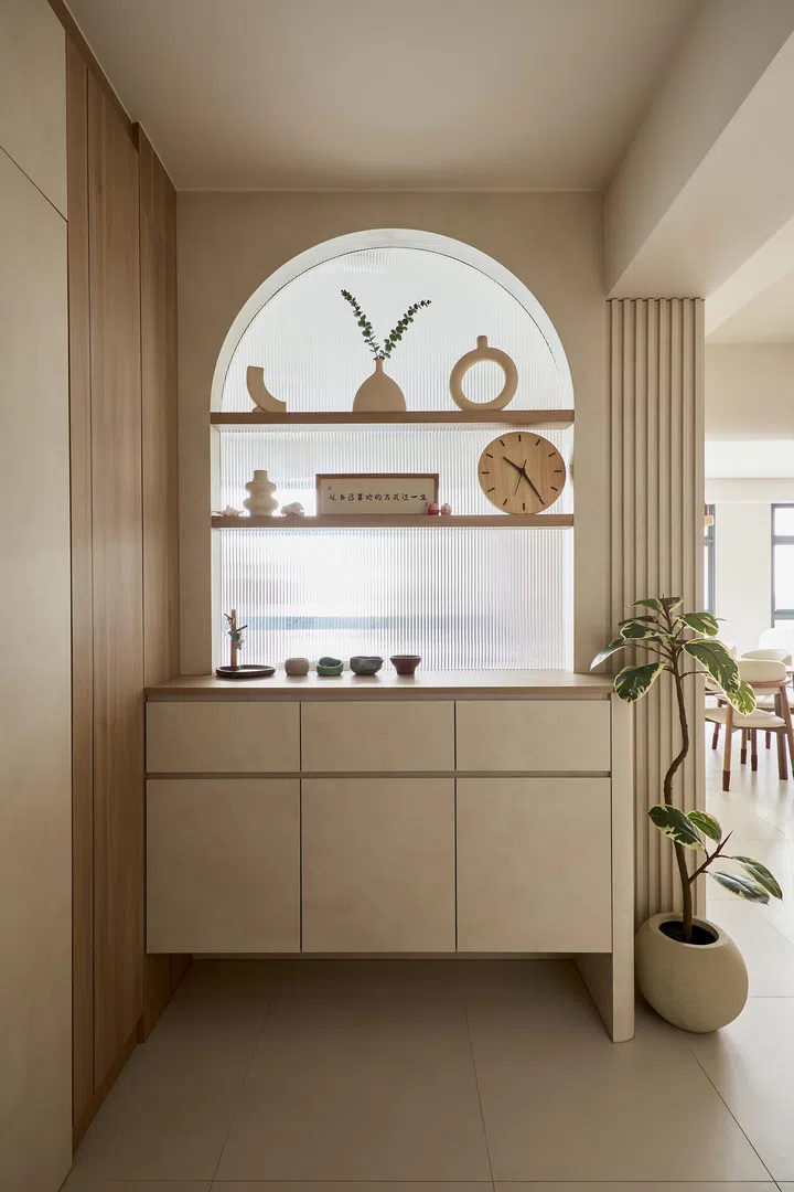 A serene entryway with fluted panels, ribbed glass, and an arched niche sets the tone for the flat.