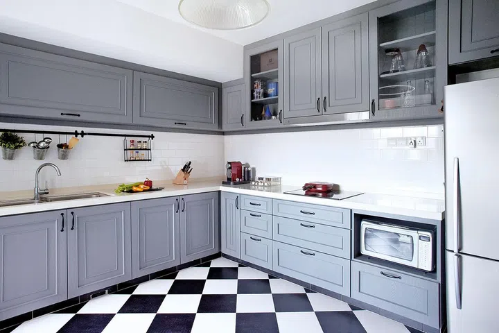 Cabinets sprayed a customised dove-grey shade, subway tiles and a chequerboard floor bear the hallmarks of a French bistro.