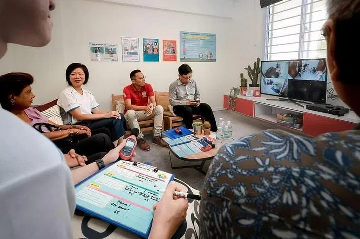 Senior Minister of State for National Development Sim Ann (second from left) and guests role-playing as “residents”. They are listening to noises made by “neighbours” while watching closed-circuit television footage of the neighbours. ST PHOTO: GAVIN FOO