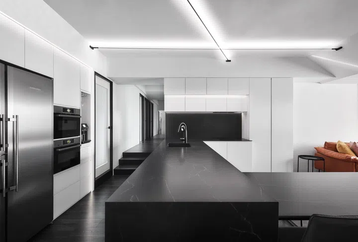 Sleek white cabinetry and dark counters streamline the reconfigured kitchen, while integrated appliances keep the design clean and functional.