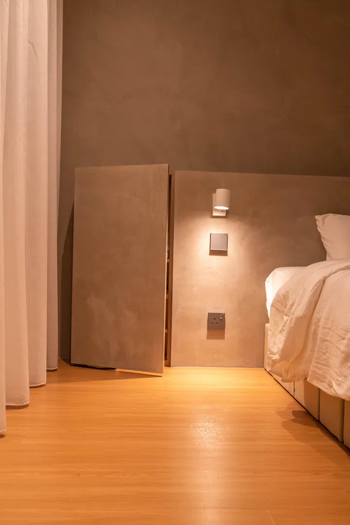 A built-in niche above the bed doubles as a ledge, softly lit by integrated warm lighting for nighttime convenience.