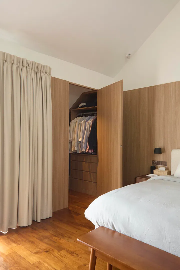  A seamless timber wall conceals the wardrobe, maintaining a clean and uninterrupted surface.