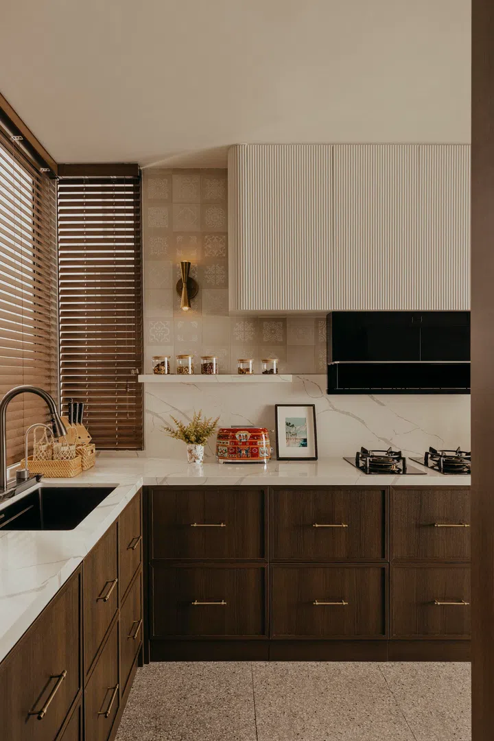 Dark wood cabinetry with pale stone and fluted tiles span the kitchen.