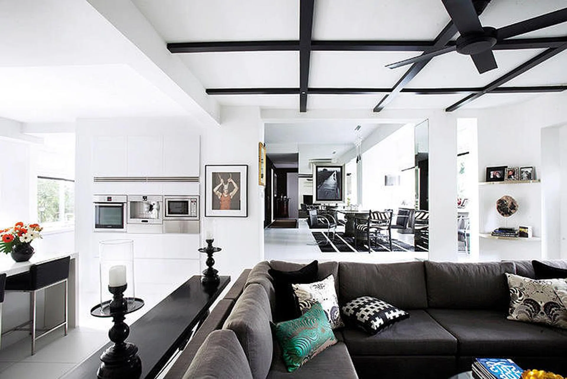 Richly hued cushions and a pair of curvy candlesticks add a feminine touch to the masculine lines and monochromatic palette of the living room.