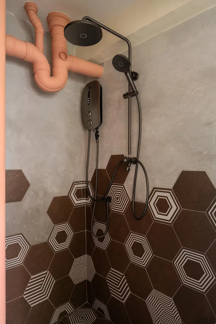 Hexagonal tiles in varied tones and patterns sweep across the bathroom like a wave, subverting the usual “accent strip” convention.