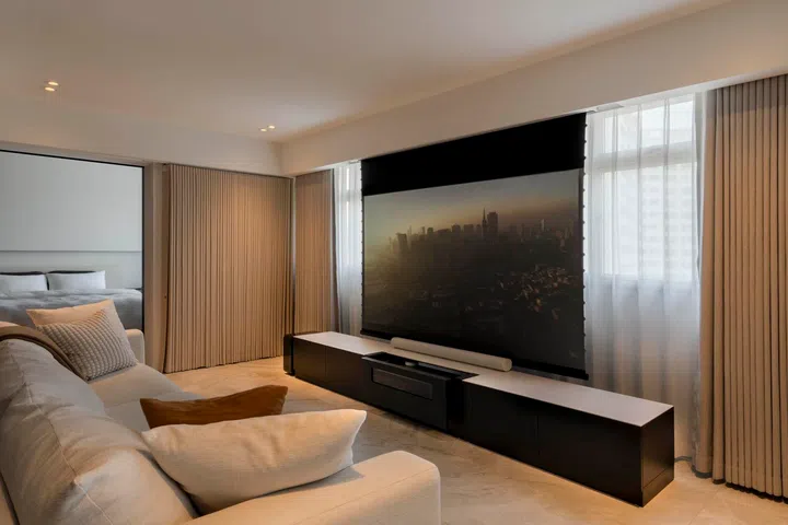 The living area is anchored by a projector-friendly wall and long sofa, designed for openness and flow.