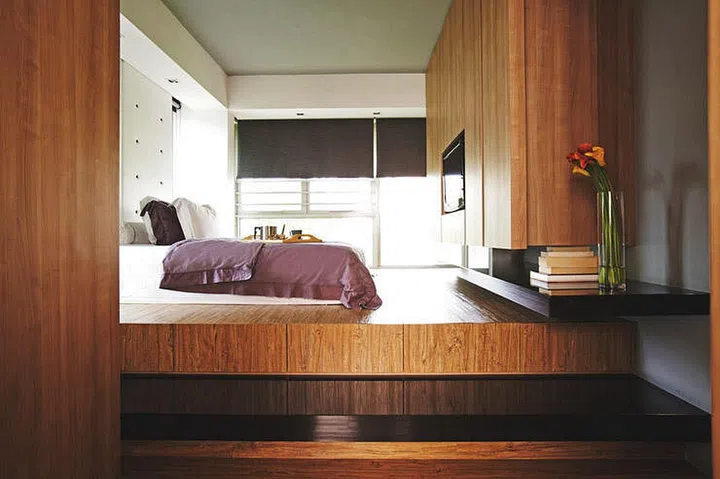 Wood platform bed in the master bedroom for a couple and their 2 children’s penthouse apartment in Yio Chu Kang.
