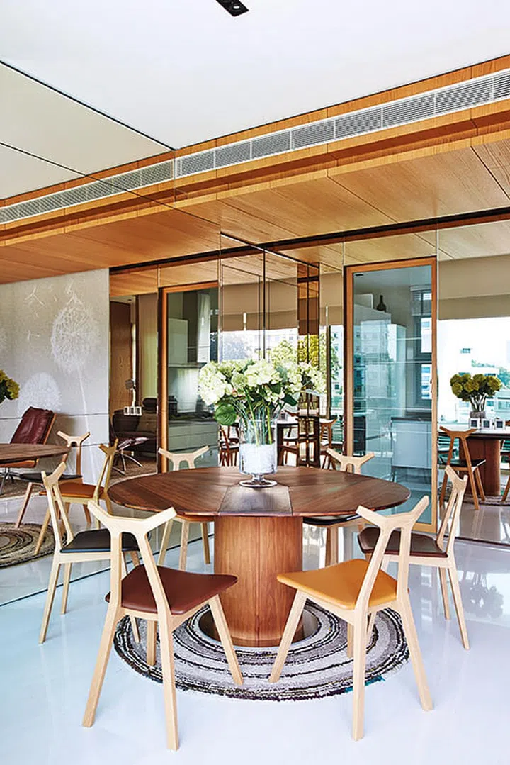 The glass kitchen door breaks up the mirrored panels that were installed beside the dining area to visually enlarge the space in William Png's white and wood 3-bedroom condominium off Orchard Road.