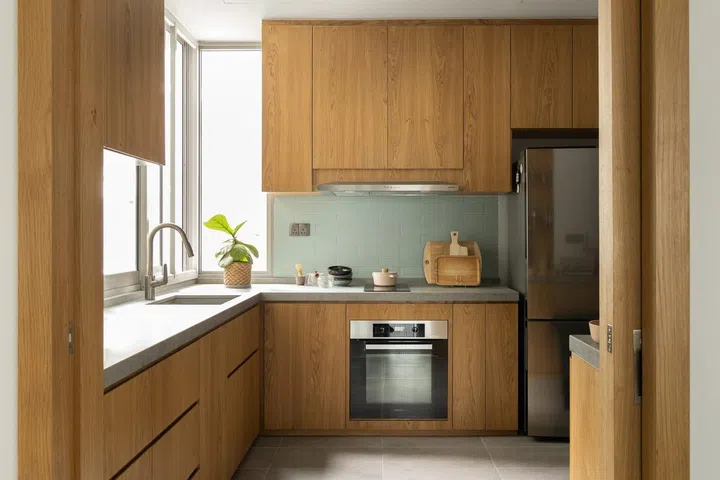 All wood kitchen cabinets with eggshell blue backsplash in this 1,900 sq ft 3-bedroom condominium in Sentosa.