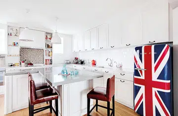 All white kitchen cabinets with a graphic, British flag SMEG fridge. Interior design by Aiden T.