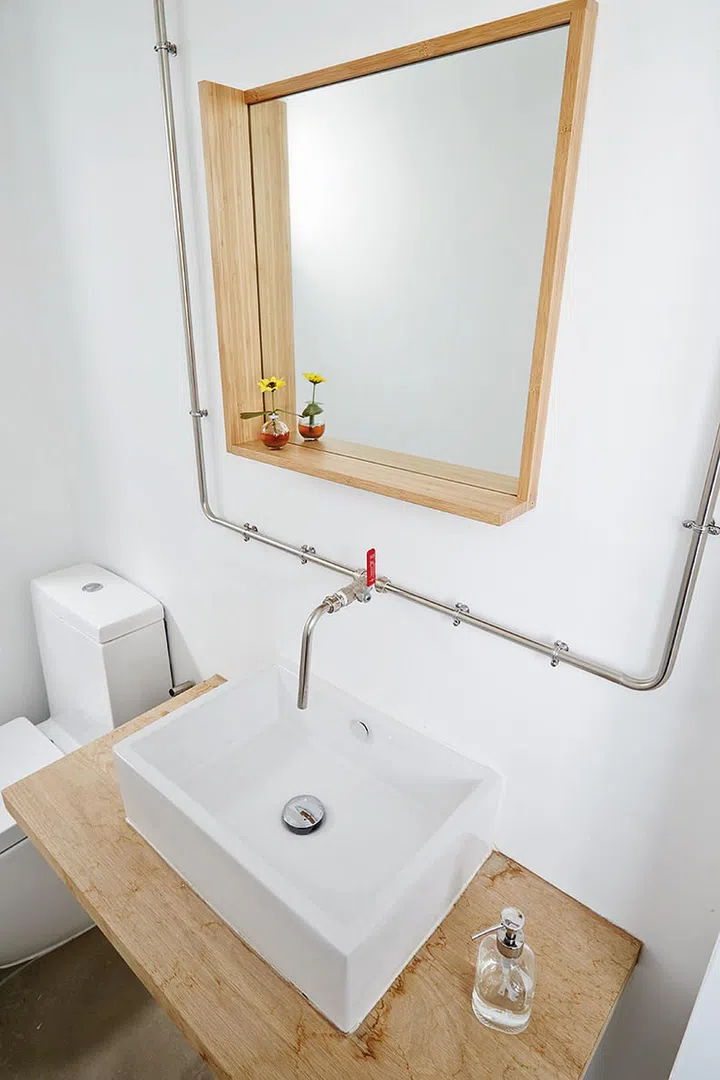 The common toilet can be accessed from the kitchen, and it echoes the home's light wood and white theme.