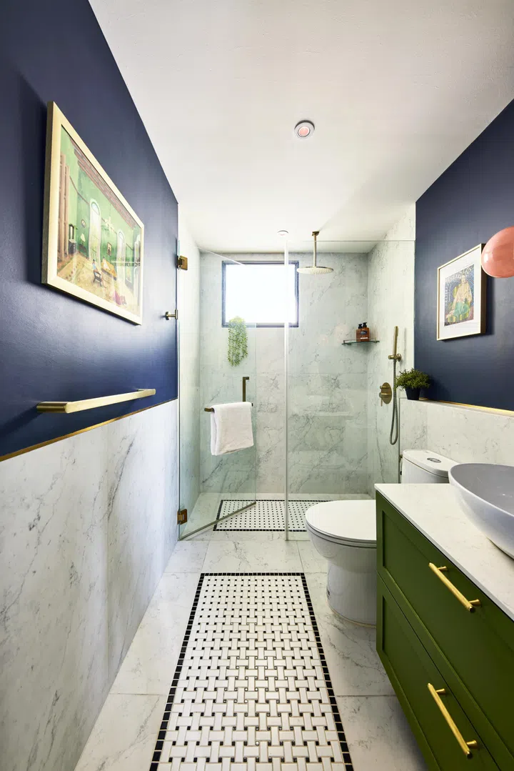 The guest bathroom boasts marble-like floor tiles that extend halfway up the walls, finished off in a navy blue paint.