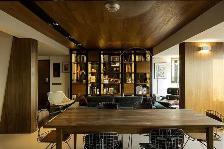 The entertaining area has a built-in walnut and teak shelf filled with pieces by avant-garde artists in this (originally) 3-bedroom condominium facing East Coast Park.