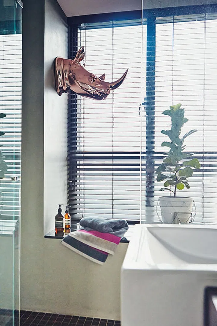 This rose-gold plated rhinoceros head jazzes up the monochromatic bathroom.