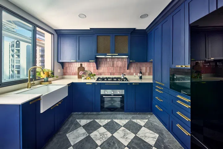 In the kitchen, indigo-coloured cabinets (constructed from wood and laminate), brass handles, and pink pearlescent backsplash tiles.