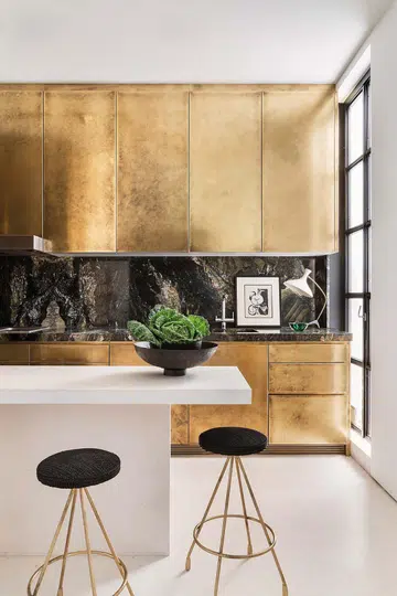 Brushed gold Bulthaup cabinetry in the kitchen area, and the black marble backsplash, makes the space feel more intimate.