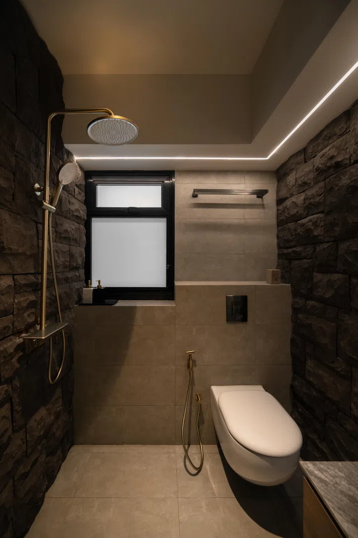 Brushed-gold fittings stand out against the dark stone, while soft lighting highlights the material’s texture.