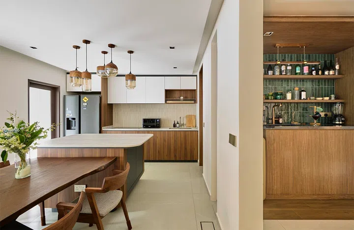 The kitchen sits just beyond the bar, continuing the timber palette while opening up into a brighter, more expansive space.